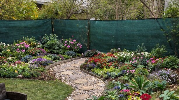 A garden with a stone pathway, wicker furniture, and a variety of colorful flowers. - Spacious Modern 3BR Free Parking 30 min to NYC (Jersey City)