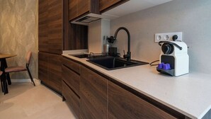 A modern kitchen with wooden cabinets, a black sink, and a built-in kettle. - VLC HOST - Palleter 1 (Valencia)