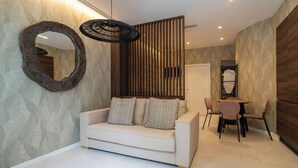 A modern living room with a sofa, a round mirror, a dining area with a table and chairs, and a decorative wall panel. - VLC HOST - Palleter 1 (Valencia)