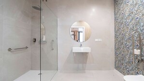 A modern bathroom with a glass shower enclosure, a round mirror, a white sink, and a toilet. - VLC HOST - Palleter 1 (Valencia)
