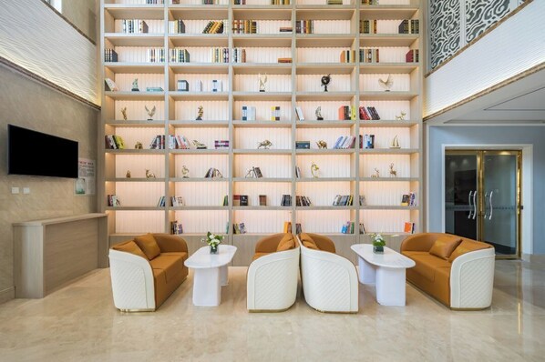 A modern lobby with a large bookshelf filled with books, a reception desk, and seating areas. - LAN WAN INTERNATIONAL HOTEL (Beijing)