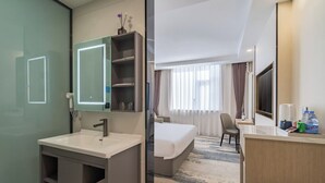 Een moderne hotelkamer met een badkamer, een bed, een bureau en een televisie.