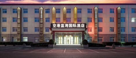 Un hôtel moderne doté d’une entrée imposante et d’un parking situé devant l’établissement.