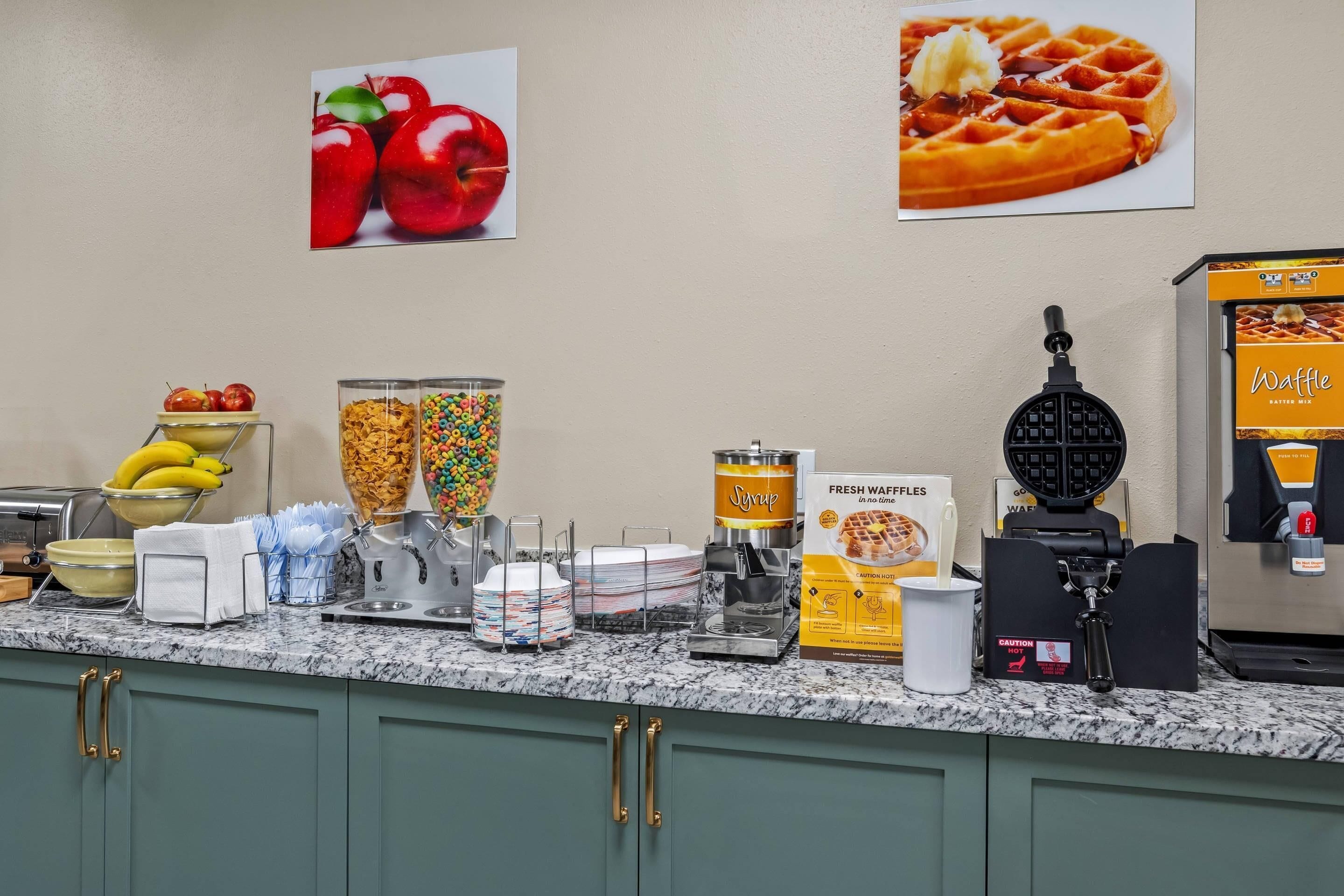 A breakfast bar with various food items and a waffle maker.