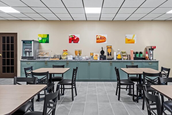 Une cafétéria avec de nombreuses tables et chaises, un distributeur de café et divers produits alimentaires exposés.