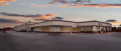 A commercial building with a flat roof and a large parking lot.