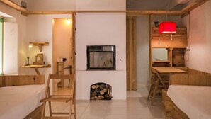 A cozy cabin-style room with two wooden beds, a television mounted on a white wall, and a small fireplace with a log storage. - Apartment Fazio by Interhome (Strongoli)