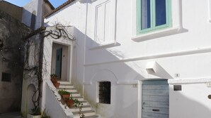 A white building with a blue door, a small window, and a staircase leading to a door marked with the number 9. - Apartment Fazio by Interhome (Strongoli)