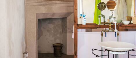 A bathroom with a wooden vanity, a mirror, a sink, and a bucket on the floor.
