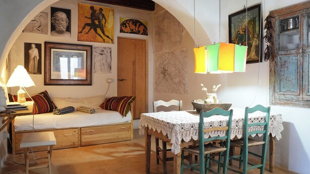 Una habitació acollidora amb un llit, una taula i cadires, i obres d'art a les parets.