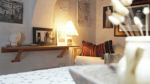 Una habitació amb un llit, una làmpada, un mapa i diverses fotografies emmarcades a la paret.