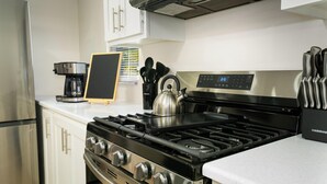 Eine moderne Küche mit Edelstahlgeräten, darunter ein Gasherd, ein Backofen und ein Kühlschrank.