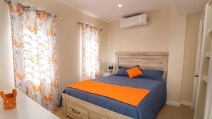 Ein Schlafzimmer mit einem Bett, einem Nachttisch, einer Lampe und einer Holzkommode.