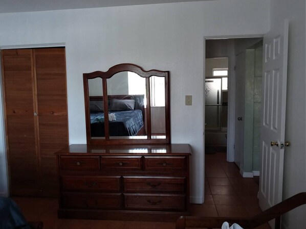 A bedroom with a wooden dresser, a mirror, and a bed. - Charming 2-bedroom cottage in enjoyable Pinellas Park with AC, WiFi, and more (Pinellas Park)