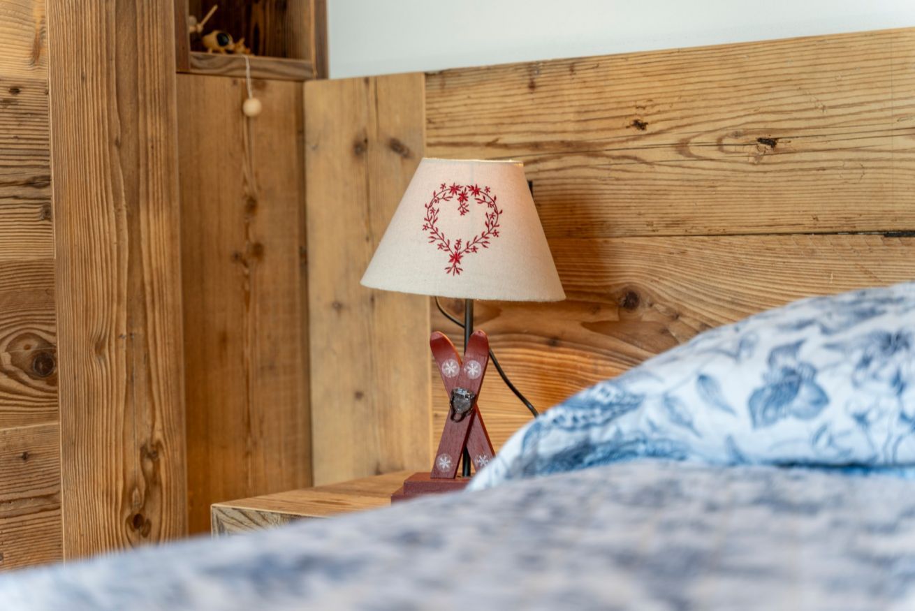 Una testiera in legno, una lampada con decorazioni floreali e una coperta dal disegno vivace.