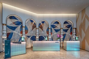 A reception area with a modern design, featuring a reception desk, decorative wall panels, and a well-lit space. - Even Yining By Ihg (Yining)