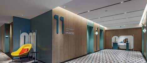 A modern hotel lobby with a patterned floor, a bright yellow chair, and a wall with a large '11' and text.