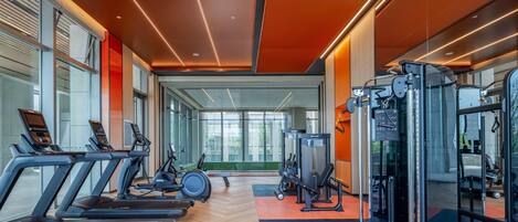 A modern gym with treadmills, weight machines, and a mirrored wall.