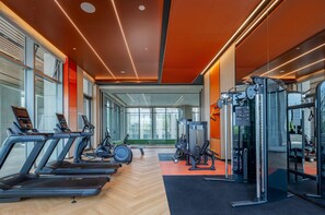 A modern gym with treadmills, weight machines, and a mirrored wall. - Even Yining By Ihg (Yining)