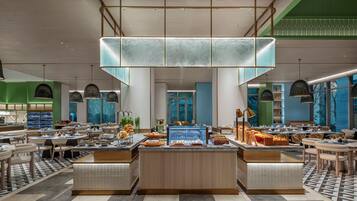 A modern hotel lobby with a central buffet, seating areas, and a view of the outdoors.