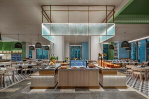A modern hotel lobby with a central buffet, seating areas, and a view of the outdoors. - Even Yining By Ihg (Yining)