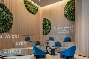 A modern lounge area with a wooden wall, blue seating, and a text message about leisure. - Even Yining By Ihg (Yining)