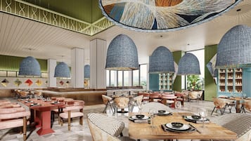 A spacious hotel lobby with high ceilings, large woven ceiling lamps, and a variety of seating arrangements including sofas and chairs.