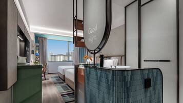 A modern hotel room with a bed, a bathroom with a mirror, and a view of the city.
