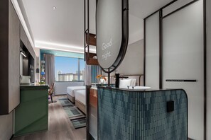 A modern hotel room with a bed, a bathroom with a mirror, and a view of the city. - Even Yining By Ihg (Yining)