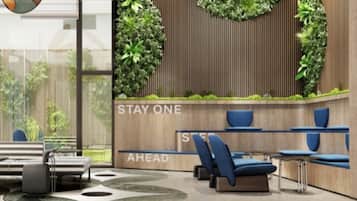 Un área de espera moderna con pared de madera, jardines verticales verdes y asientos azules.