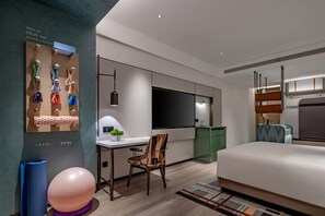 A modern hotel room with a bed, a desk with a chair, a TV, and exercise equipment. - Even Yining By Ihg (Yining)