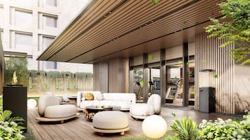 An outdoor seating area with a modern design, featuring a wooden deck, stone seating, and a glass wall.