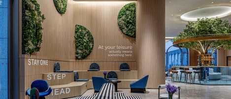 A modern hotel lobby with a reception desk, seating area, and a large indoor garden.