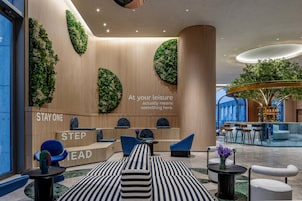 Un moderno vestíbulo de hotel con mostrador de recepción, zona de estar y un gran jardín interior.