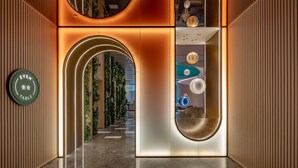 Ein modernes Interieur mit einer gebogenen Rezeption, einem Schild, das einen Essbereich kennzeichnet, und einer Treppe, die zu einer weiteren Ebene führt.