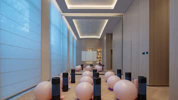 A modern hotel interior with exercise balls and weights, a long corridor, and a reception area in the distance.