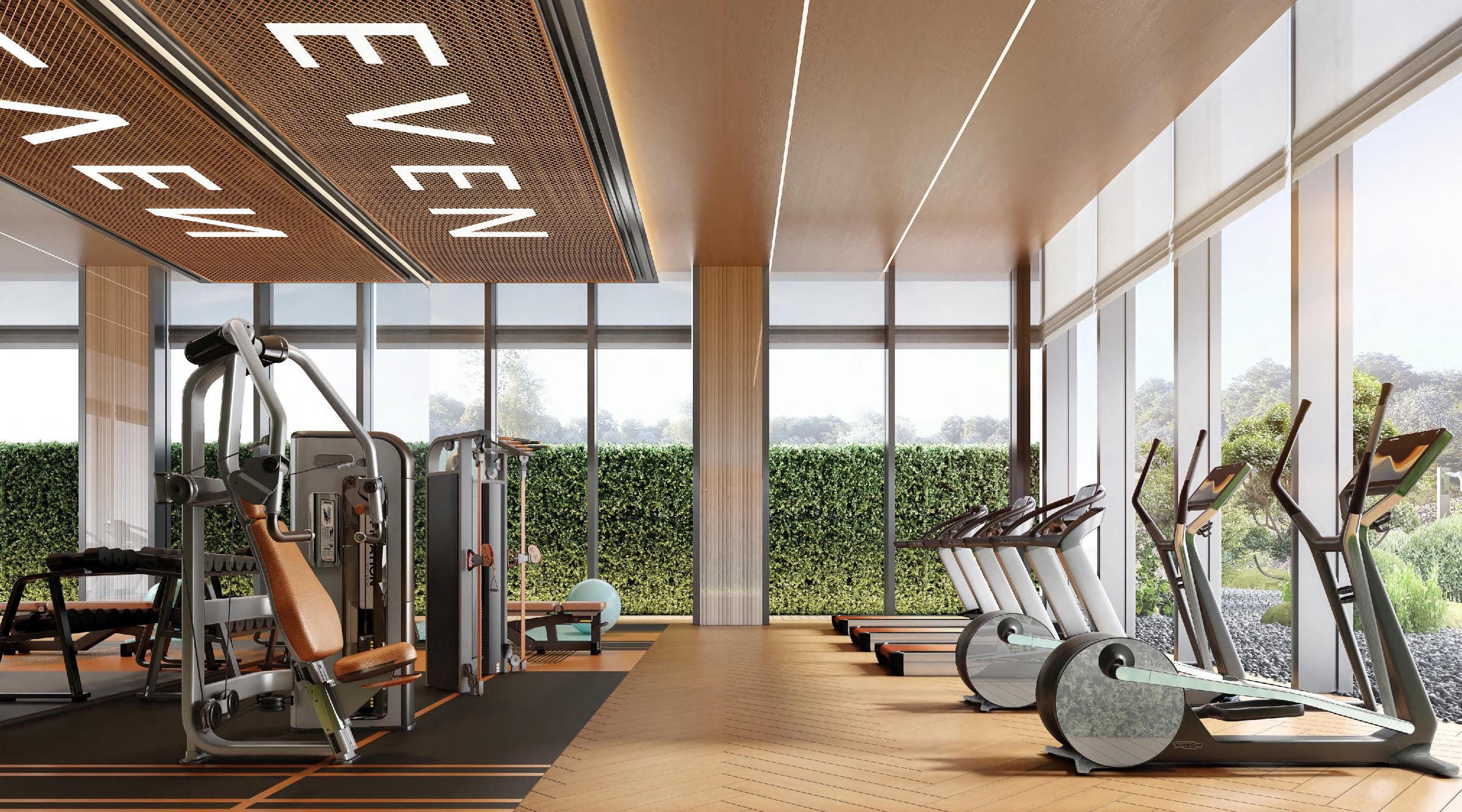 Een moderne sportschool met trainingsapparatuur, grote ramen en uitzicht op groen.