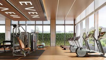 Een moderne sportschool met trainingsapparatuur, grote ramen en uitzicht op groen.