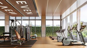 A modern gym with exercise equipment, large windows, and a view of greenery. - Even Yining By Ihg (Yining)