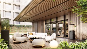 Ein Sitzbereich im Freien mit modernem Design, ausgestattet mit einem Holzdeck, Steinsitzgelegenheiten und einer Glaswand.
