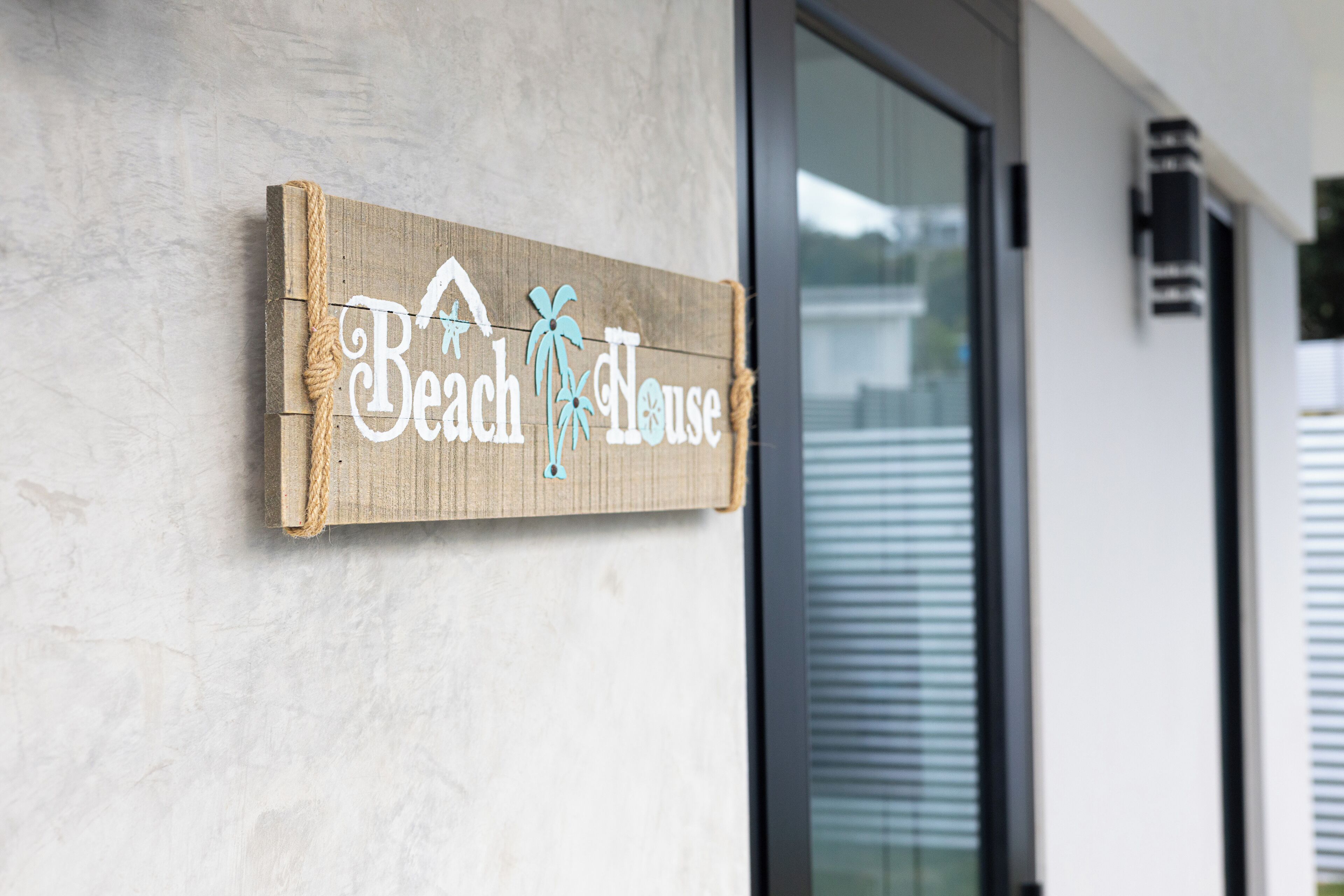 A wooden sign with the text "Beach House" and a palm tree graphic.