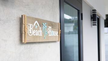 A wooden sign with the text "Beach House" and a palm tree graphic.