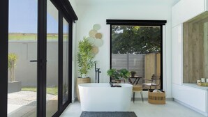 Une salle de bain moderne avec une baignoire sur pieds, de grandes fenêtres et une vue sur l’extérieur.