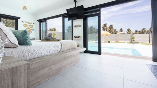 Une chambre moderne avec un grand lit, une télévision et une vue sur une piscine.