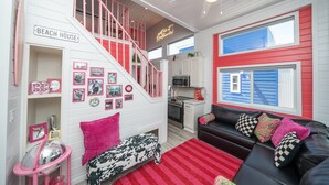 A multi-level interior with a staircase, a kitchen, a seating area, and a sign reading "BEACH HOUSE". - The Boozy Bungalow at Roadrunner Resort (Parker)