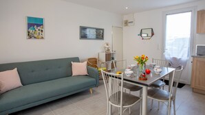 Un salon moderne comprenant un canapé, une table à manger, des chaises et un coin cuisine.