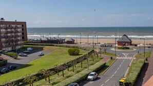 A coastal view with a road, buildings, and a beach.
