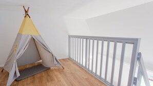 A room with a wooden floor, a grey and yellow tent, and a white railing.