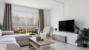 A modern living room with a sofa, a coffee table, a TV, and a balcony with outdoor seating. - Erisa 1-29. Terrace, Swimming Pool, Second line of beach (Torremolinos)