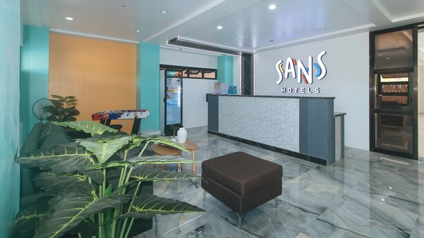 A reception area with a foosball table, a refrigerator, and a seating area with a brown ottoman. - Sans Hotel near Enchanted Kingdom (Santa Rosa)